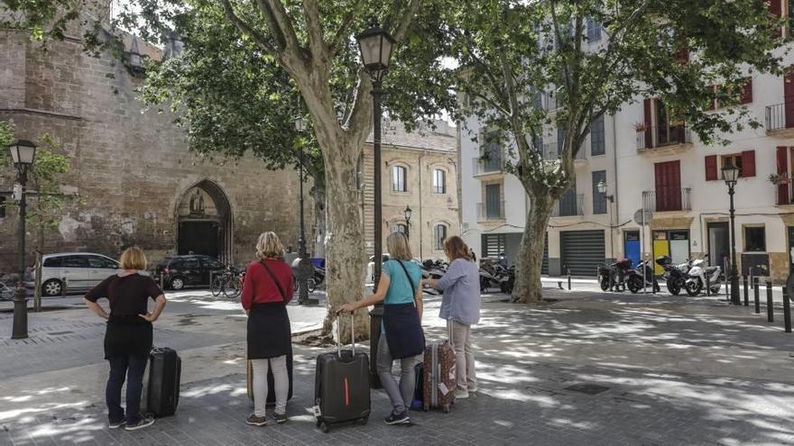 Cuatro turistas con maletas de ruedas esperan a ser recogidas en la plaza Llorenç Bisbal, en Palma.  b. ramon