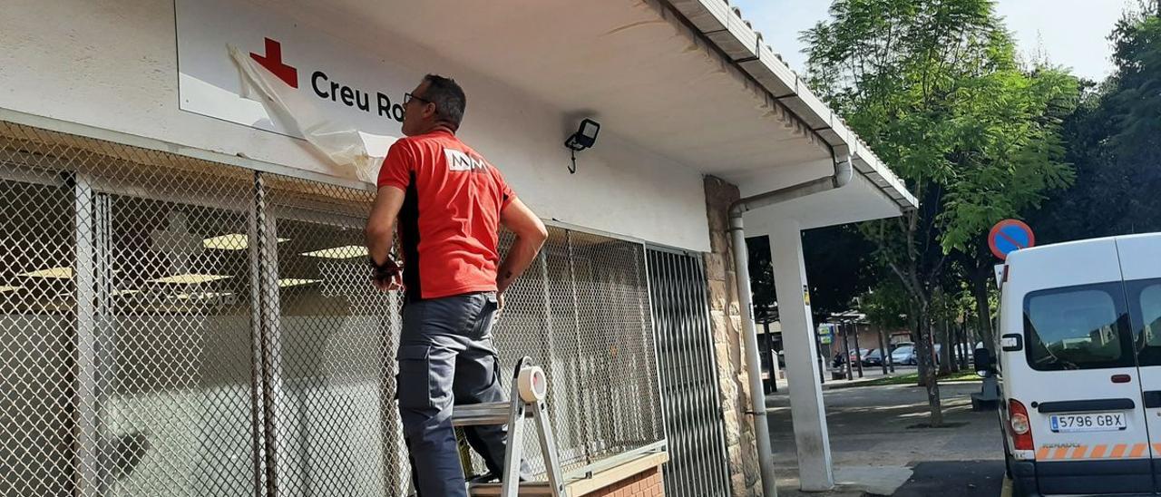 Un operario coloca el rótulo de Cruz Roja en la fachada de su nueva sede, en la Estacioneta de la Panderola.