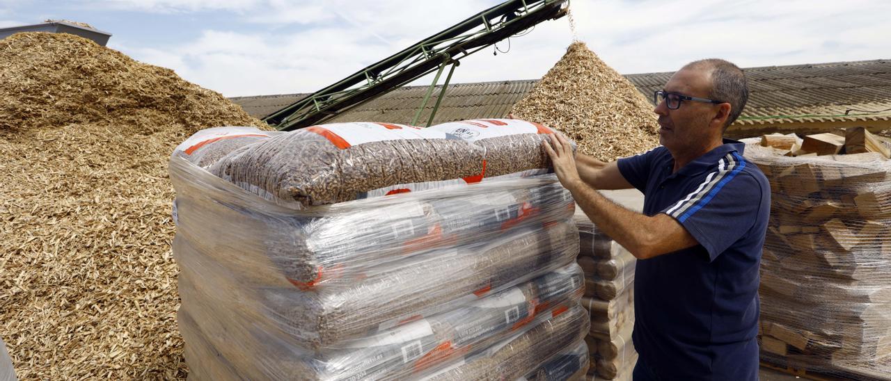 Javier López, de la empresa Comdisa Biomasa, junto a unos sacos de pellets y montañas de astilla.