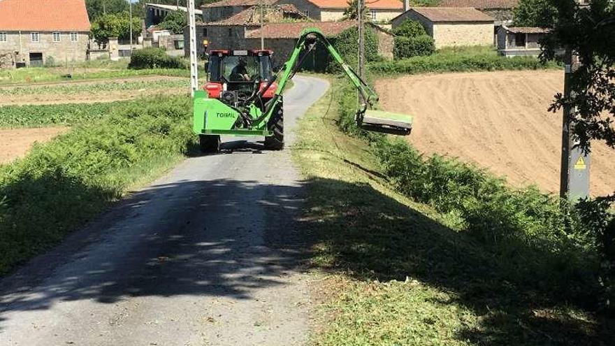 Uno de los tractores limpia las cunetas de una pista de Pazos.