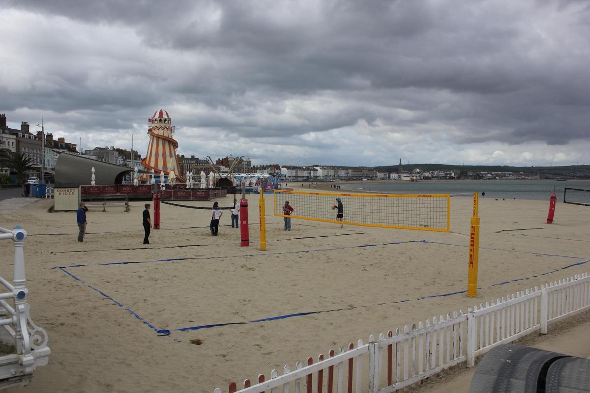 Solicitantes de asilo del Bibby Stockholm juegan a vóley en una playa de Weymouth.
