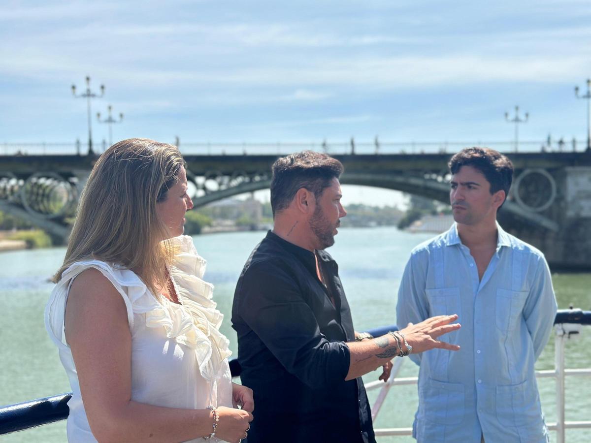 Ángela Moreno, Miguel Poveda y Luis Ybarra durante un encuentro con los medios cruzando el río Guadalquivir.