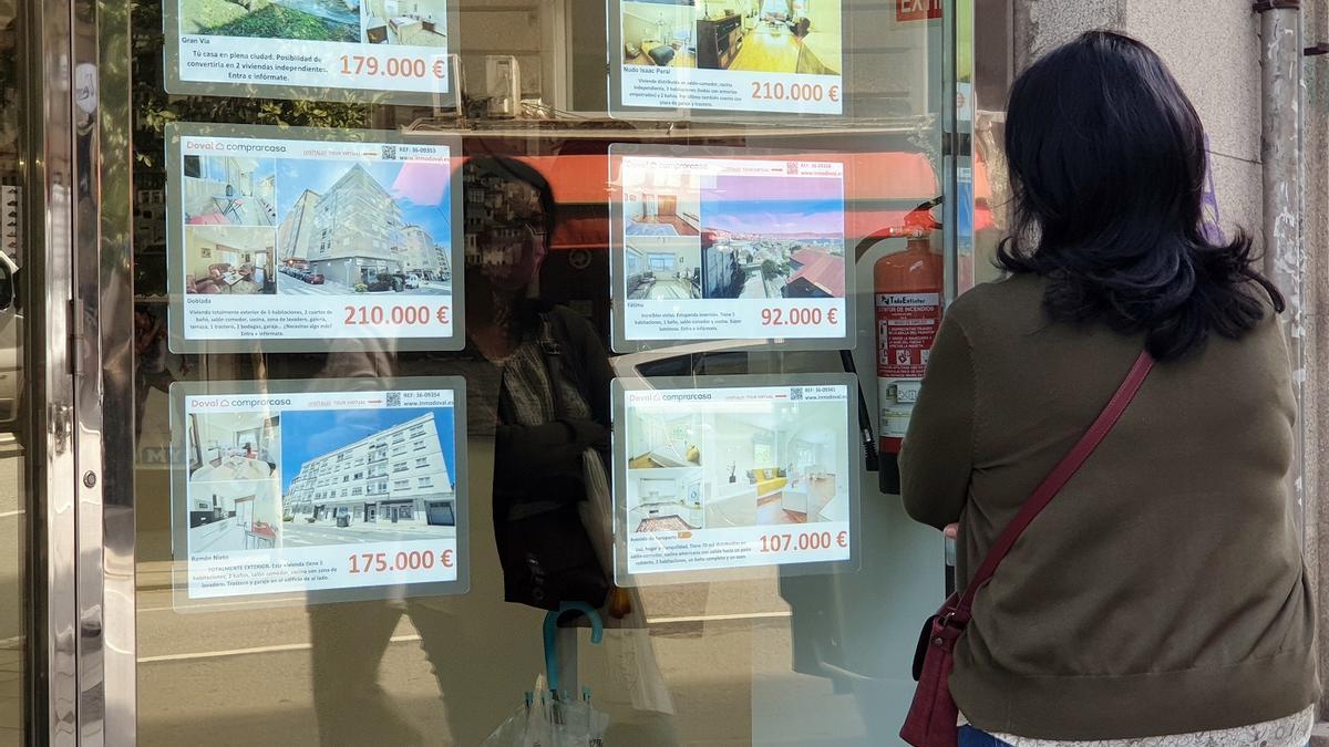 Una mujer mira anuncios de pisos en una inmobiliaria de Vigo
