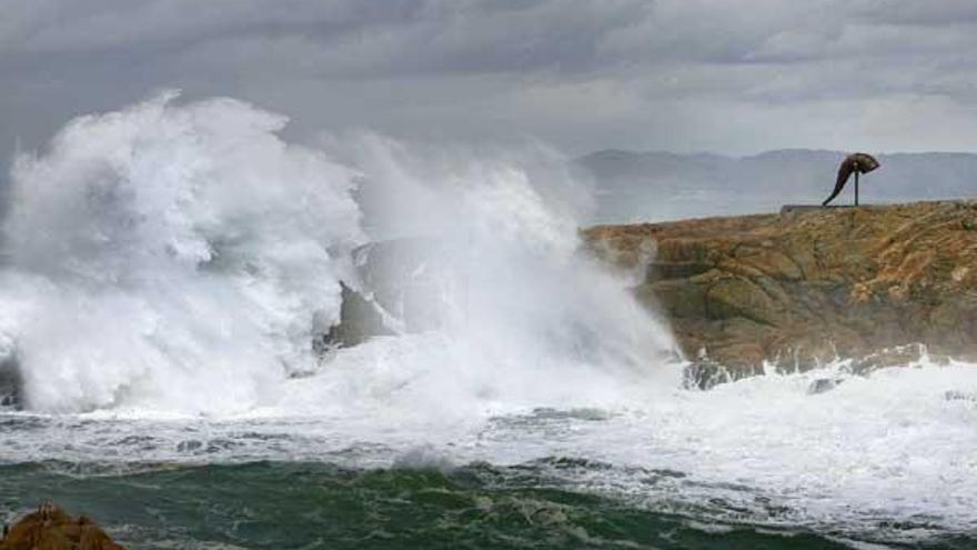 Una gran ola rompe contra las rocas de Punta Herminia, en las inmediaciones de la Torre de Hércules de A Coruña