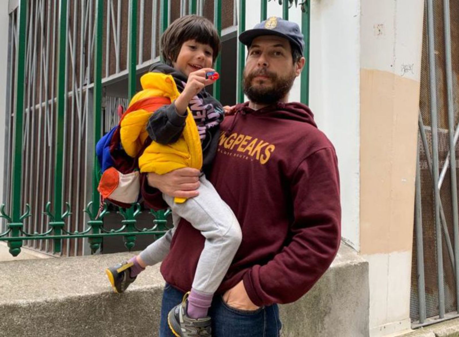 Rubén Quirós sostiene a su hijo Blas frente a las instalaciones del colegio Jovellanos de Gijón.