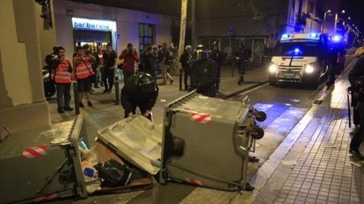 Contenedores tumbados y coches de la policía, anoche, en Gràcia.