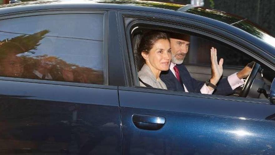 Los Reyes y sus hijas saludan a los reporteros desde el coche a su llegada al centro escolar.