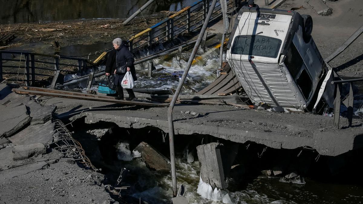 Una mujer cruza un puente destruído en la localidad de Irpin durante la evacuación de civiles