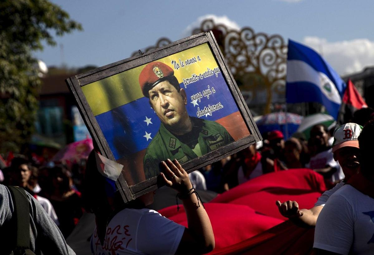 AME3159  MANAGUA  NICARAGUA   04 03 2019 - Una mujer sostiene un cartel con la imagen del expresidente de Venezuela Hugo Chavez Frias durante una caminata encabezada por la Juventud Sandinista y la embajada de Venezuela en Nicaragua este martes para recordar el aniversario numero seis de su muerte  en la avenida  De Bolivar a Chavez   en Managua  Nicaragua   Chavez fallecio el 5 de marzo de 2013 a causa de un cancer contra el que lucho por casi dos anos  EFE Jorge Torres