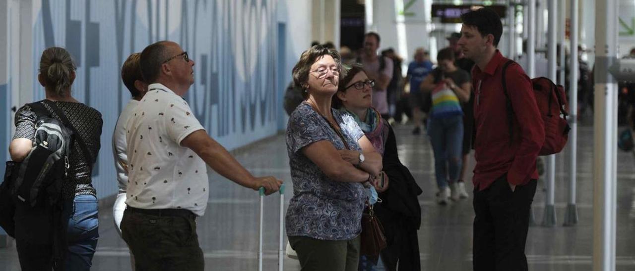 Turistas observan los paneles de información en el aeropuerto.