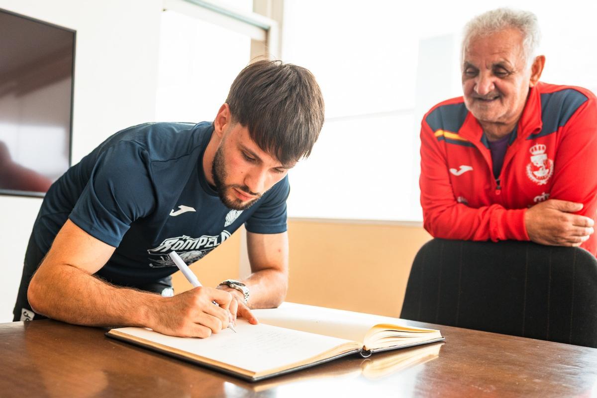 Dani Fernández firmando esta mañana en el Libro de Honor del Concello de Cangas ante la presencia del edil de Deportes, Eugenio González.