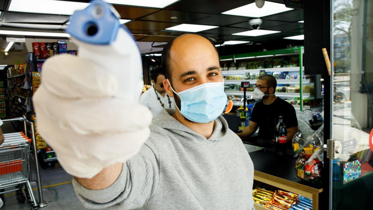 Un home prenent la temperatura amb mascareta