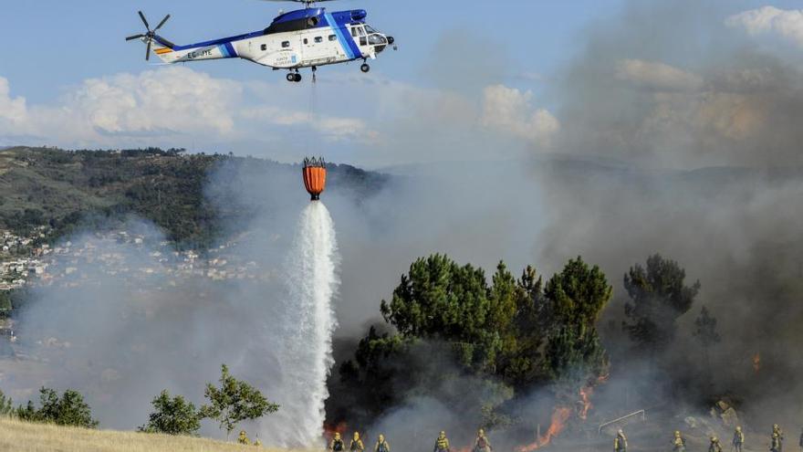 Un helicóptero y un equipo de brigadistas trabajan en las labores de extinción del incendio. // Brais Lorenzo