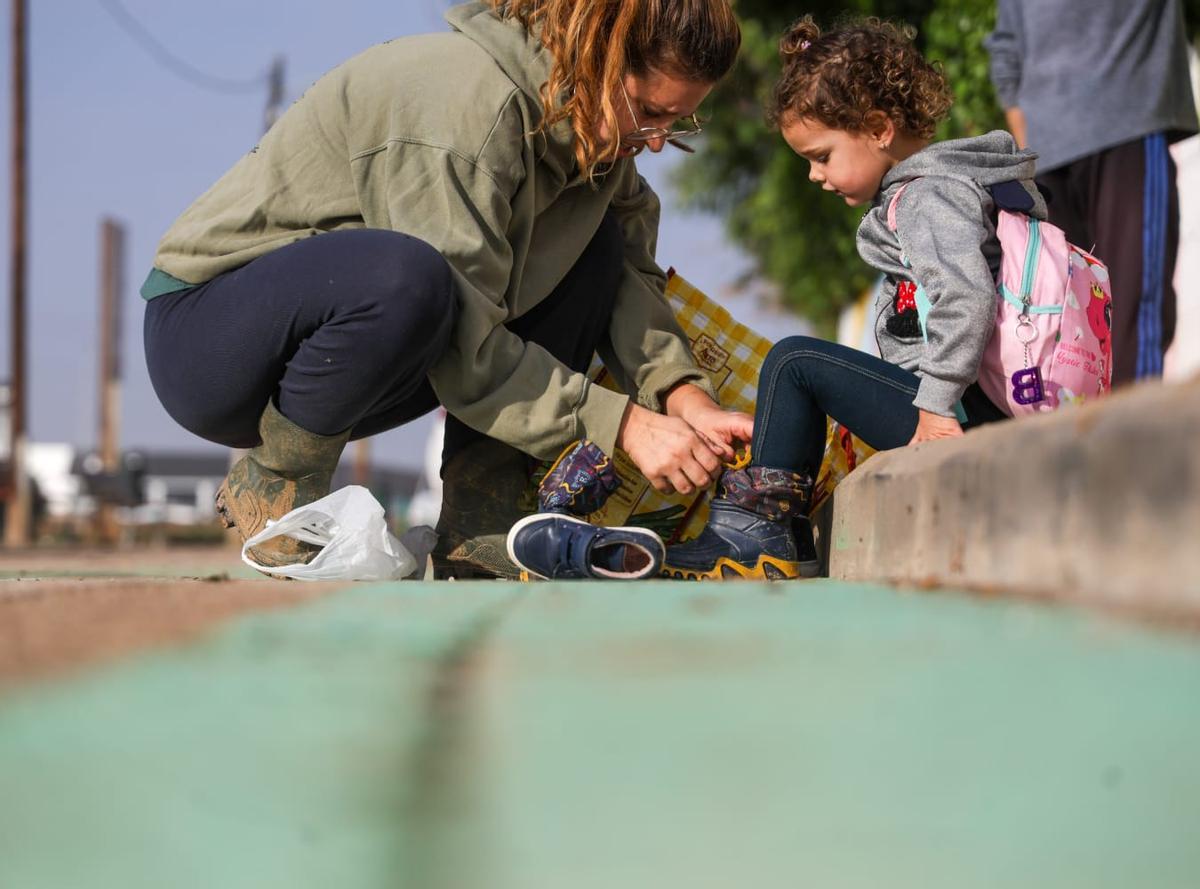 Una madre cambia de zapatos a su hija, antes de entrar al cole.