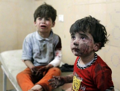 Injured children cry after, according to activists, two barrel bombs were thrown by forces loyal to Syria's president Bashar Al-Assad in Aleppo