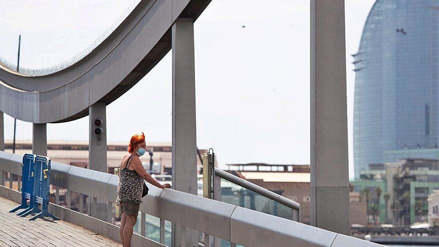 Una dona observa el port de Barcelona amb la mascareta.