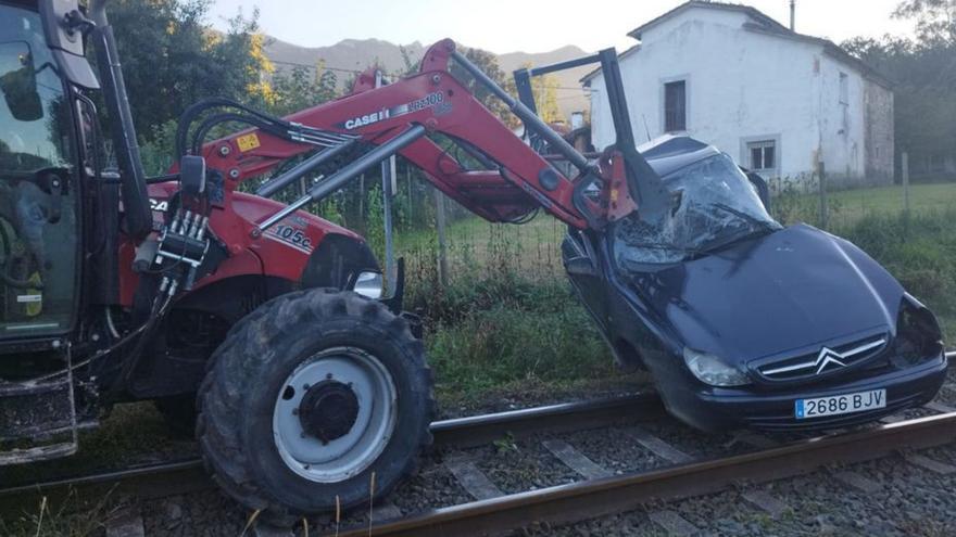 Un tractor retira el coche arrollado por el tren en un paso a nivel sin barreras de San Roque del Acebal. | J. Q.