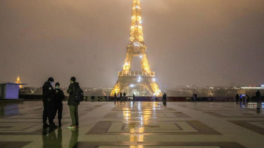 Un policía habla con unos ciudadanos cerca de la Torre Eiffel.