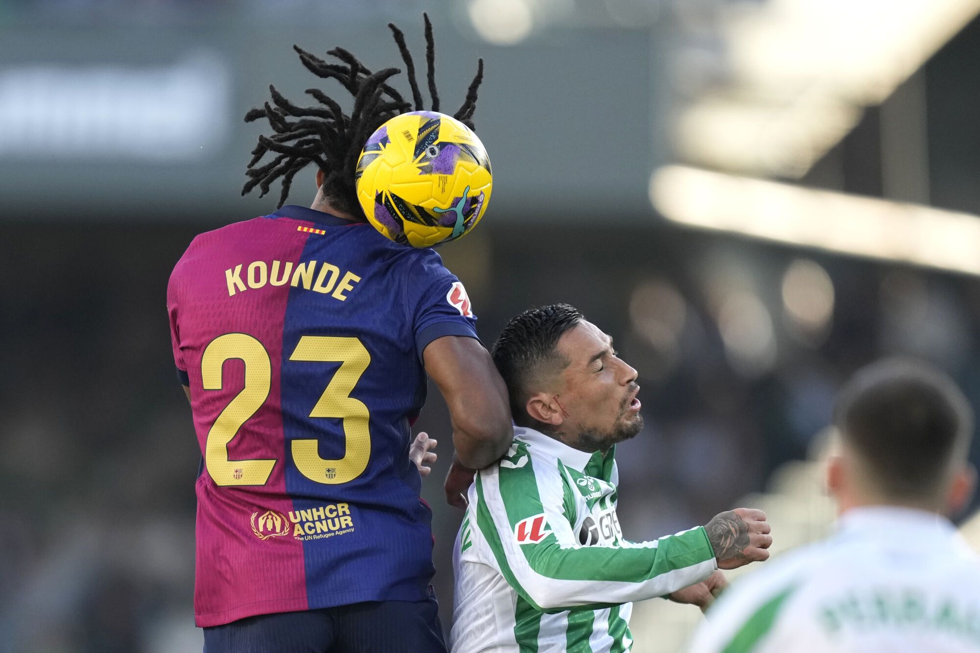Barcelona's Jules Kounde, left, challenges for the ball with Betis' Chimy Avila during a Spanish La Liga soccer match between Betis and Barcelona at the Benito Villamarin stadium in Seville, Spain, Saturday, Dec. 7, 2024. (AP Photo/Jose Breton)