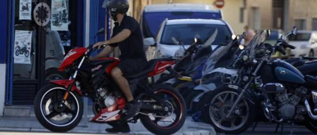 Un joven parado en una esquina con su motocicleta.