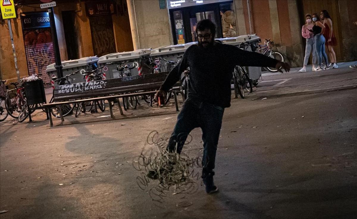 Un hombre chuta una estructura que representa el covid tras la finalización del toque de queda en la plaza del ayuntamiento de Gràcia.