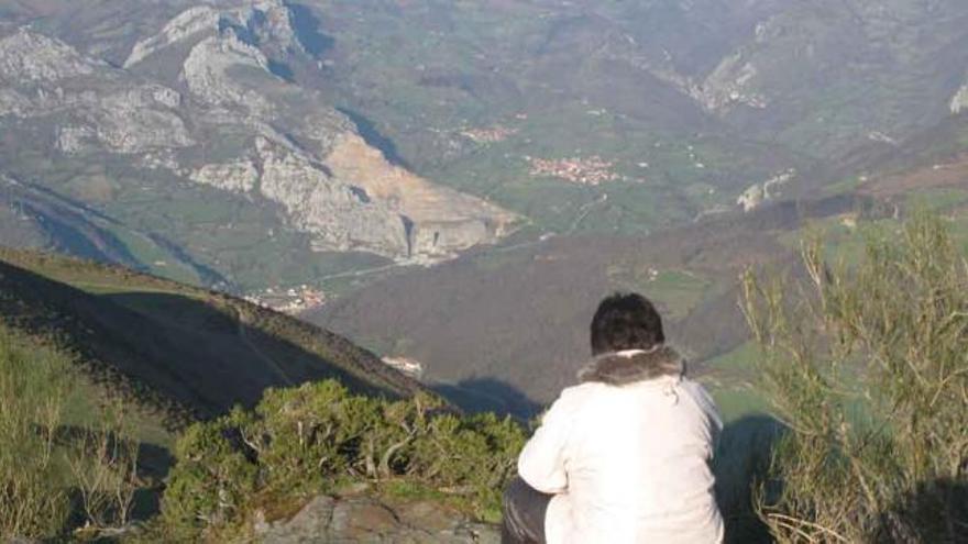 Una mujer observa la cantera de Pelúgano, cuyas cortas se aprecian al fondo.