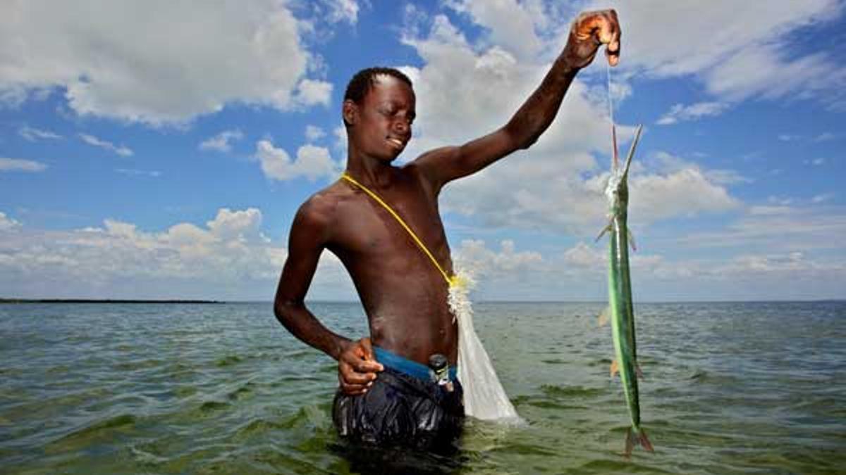 Joven pescador posando con su captura -un pez espada- en la costa de la Isla de Ibo.