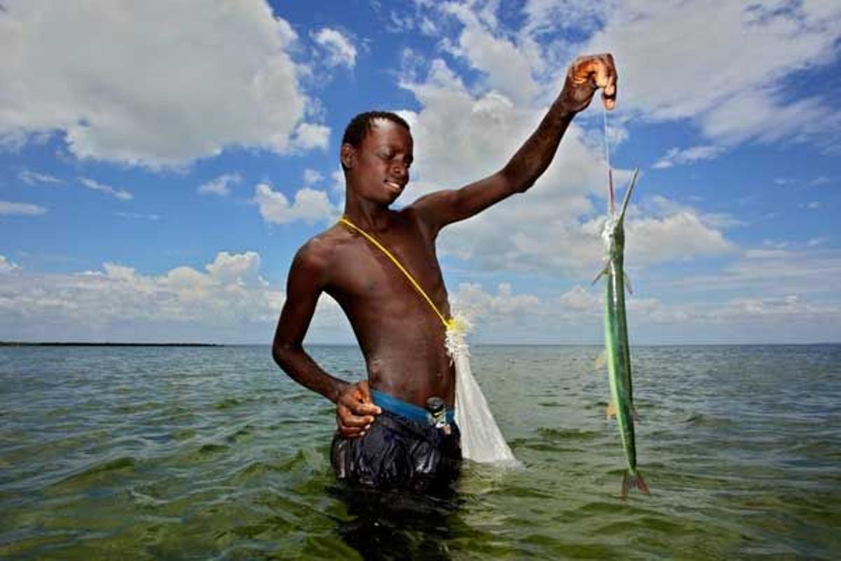 Joven pescador posando con su captura -un pez espada- en la costa de la Isla de Ibo.