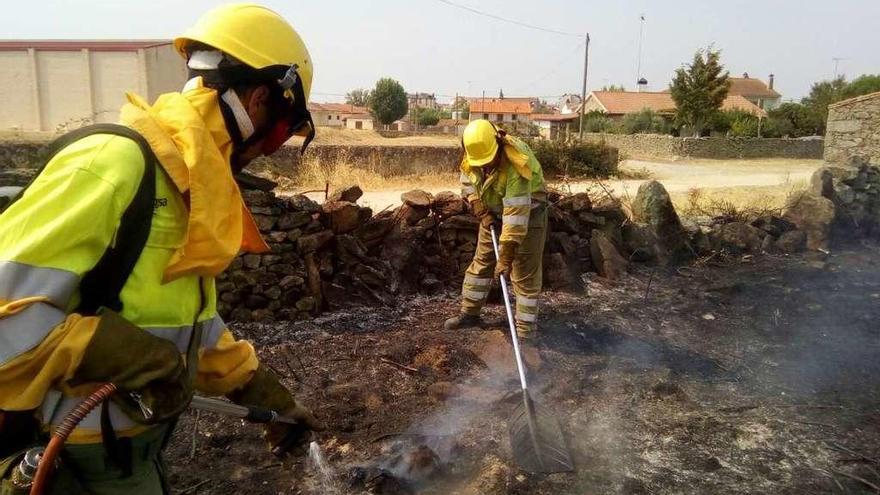 Dos trabajadores del operativo contra incendios trabajan en la zona del fuego en Muga.