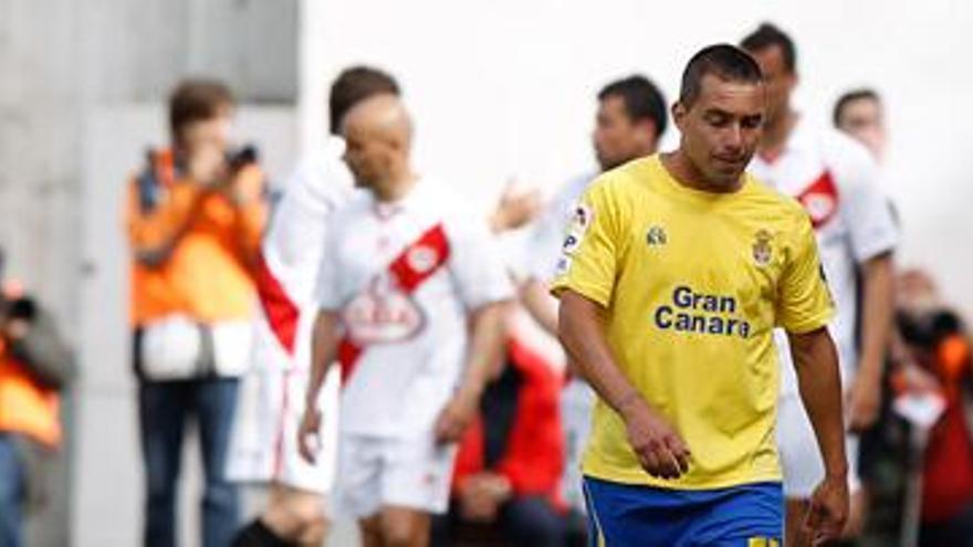 Pedro Vega, cabizbajo, camina ayer sobre el césped del estadio Teresa Rivero, mientras Sergio Suárez yace en el suelo rodeado de jugadores del Rayo Vallecano. i LOF