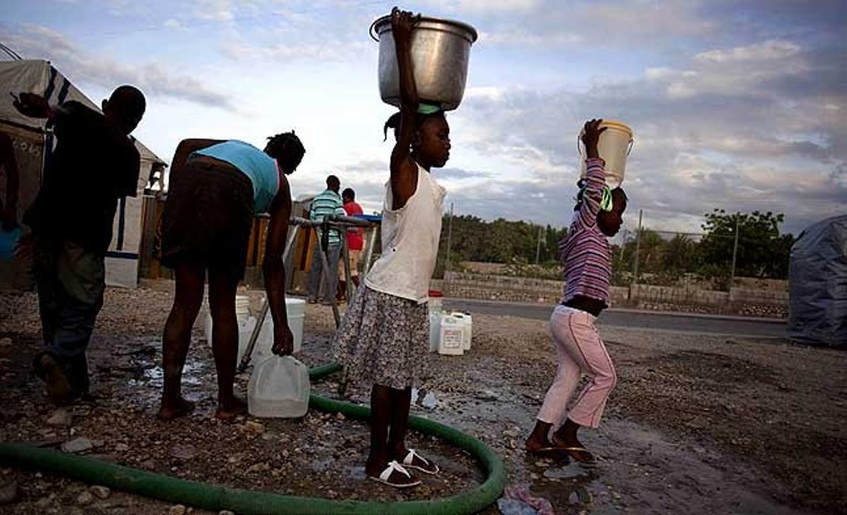 Dues nenes porten aigua a un campament per a persones desplaçades pel terratrèmol de Port-au-Prince (Haití). Més de 220.000 persones van morir i milers es van quedar sense llar.
