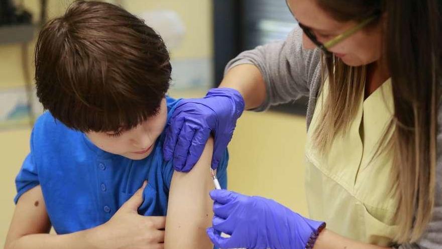 Una sanitaria inyecta una vacuna a un niño en un centro médico de Santiago.