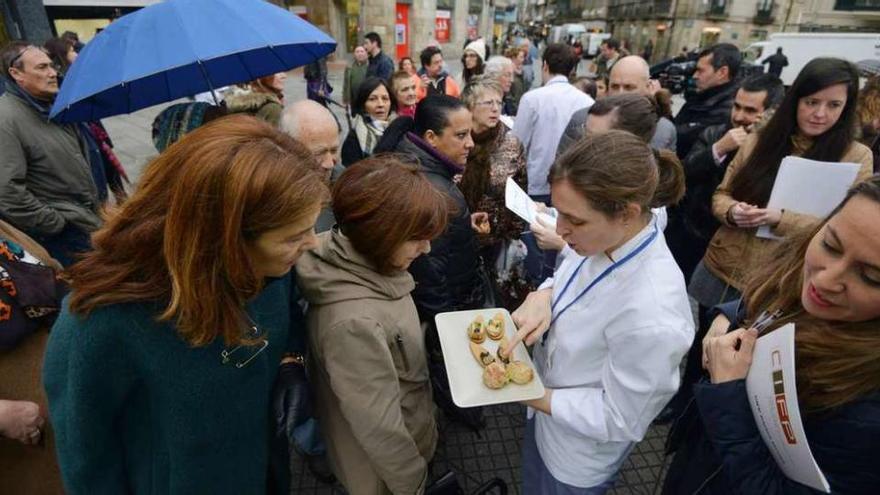 Una de las 80 alumnas que participa en el proyecto ofrece a una ciudadana un bocado para degustar.