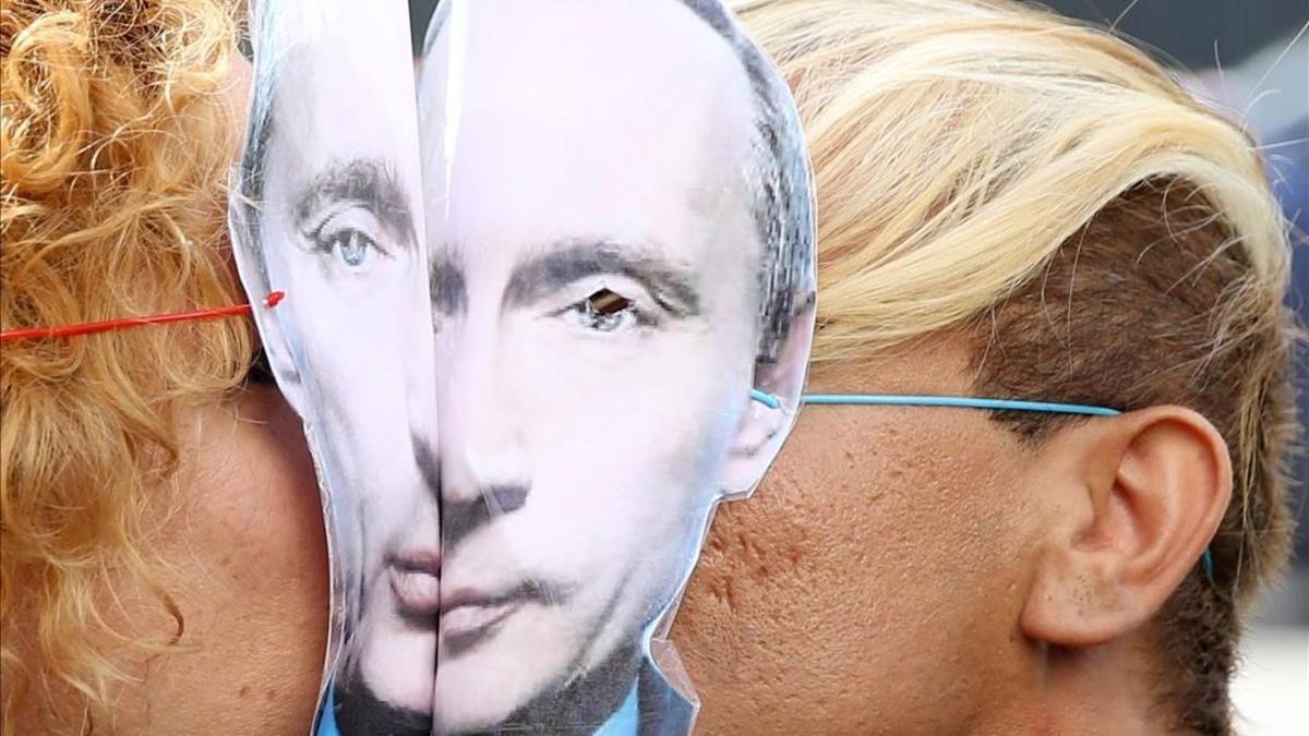 Una pareja se besa durante una protesta contra la discriminación de personas LGTBI con sendas caretas de Vladimir Putin.