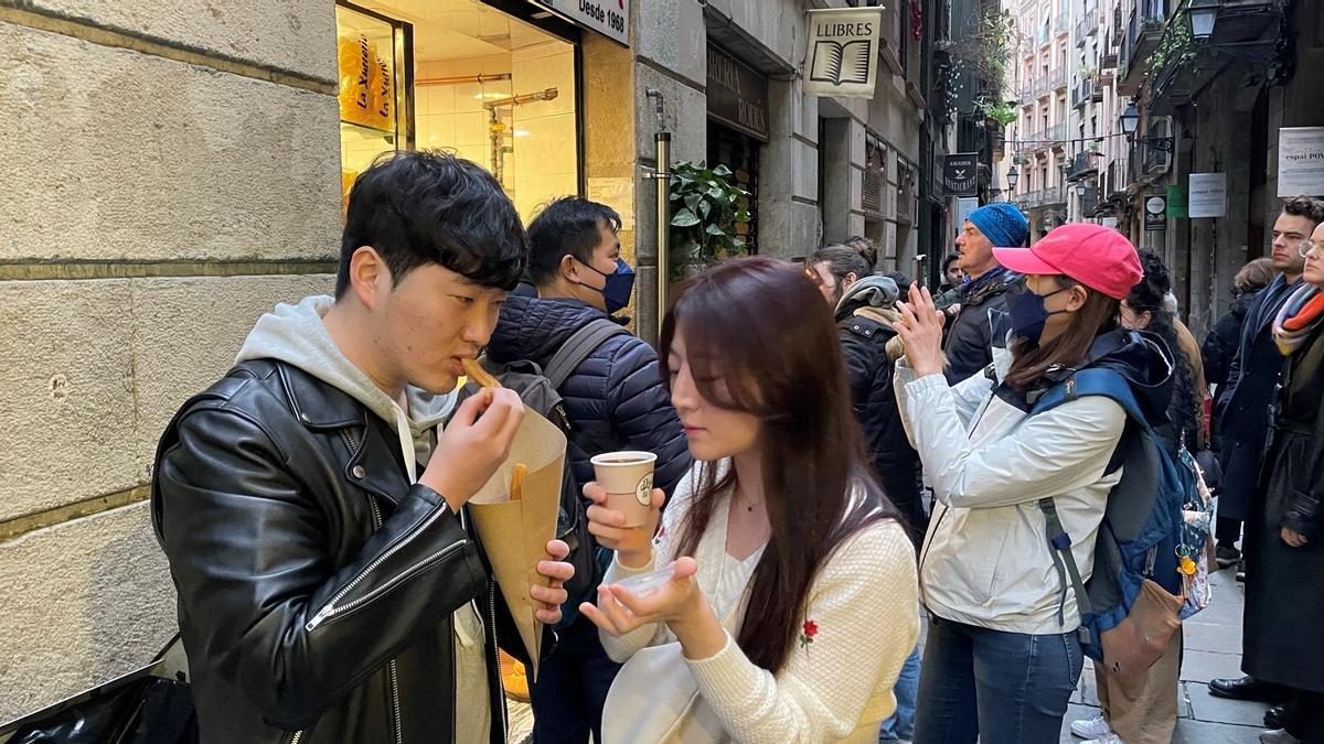 Una pareja de coreanos prueba por primera vez los churros a la puerta de la churrería.