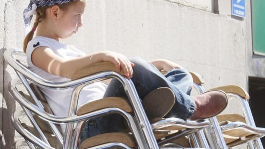 Una niña descansa sobre unas sillas de terraza en Valencia.