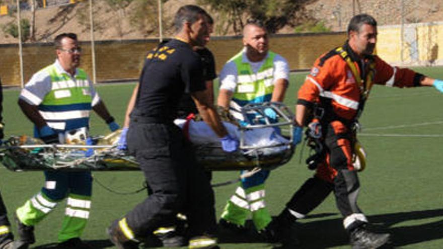 Bomberos, sanitarios y personal de Emergencias llevan a una de las víctimas al helicóptero que la trasladó desde el campo de fútbol de Mogán al centro hospitalario, ayer. iGIORGIO RAPETTI