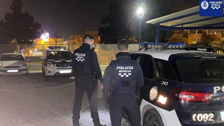 Dos policías locales de Murcia junto a su coche patrulla.