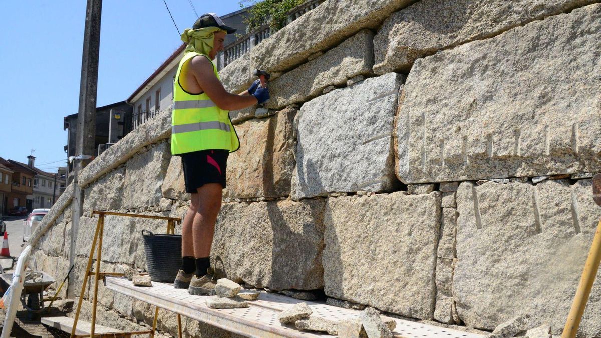 Un obrero, ayer, trabajando en un muro en Bueu y tratando de cubrirse del sol.
