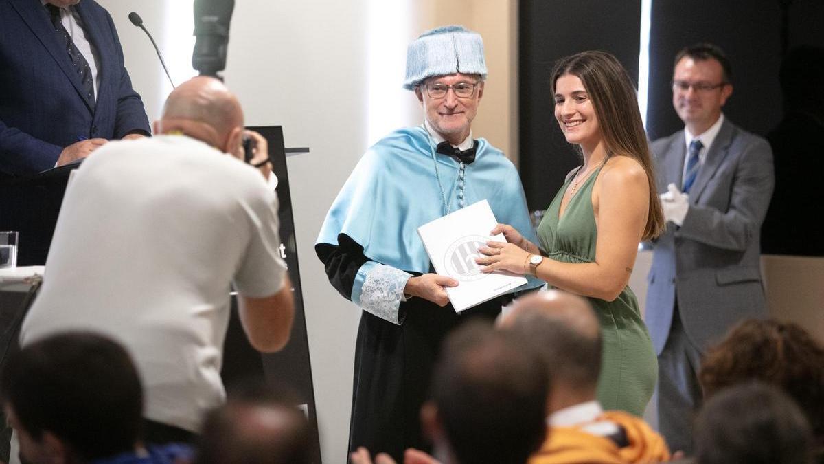 Una alumna graduada posa con su título