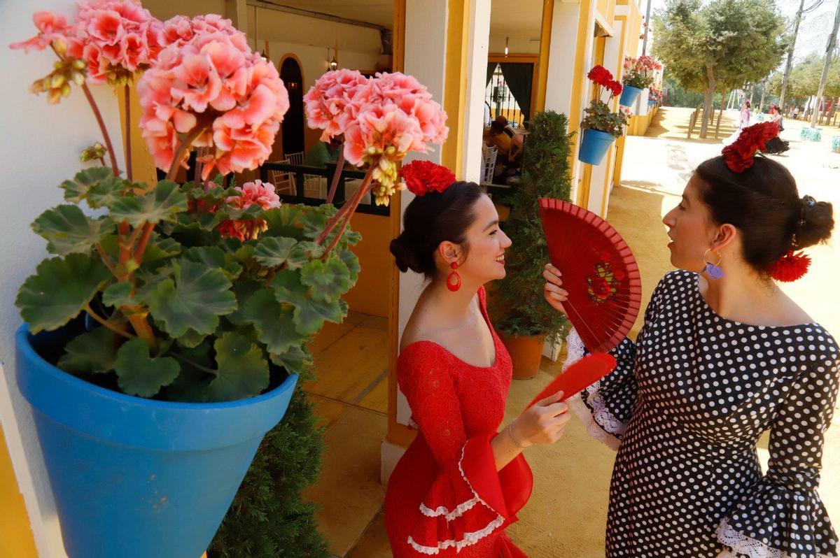 Dos jóvenes se abanican a la entrada de una caseta de la Feria de Córdoba, este viernes.
