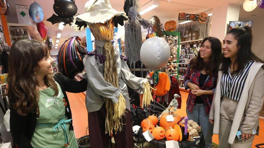 Melisa muestra a sus clientes diferentes artículos de Halloween de su tienda.