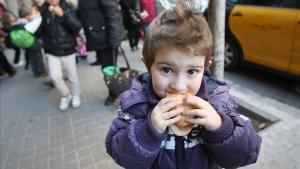 Un niño come un bocadillo a la salida del colegio.