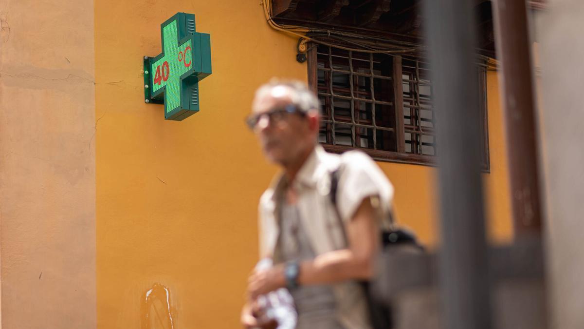 Un termómetro marca 40 grados mientras un hombre pasea por La Laguna