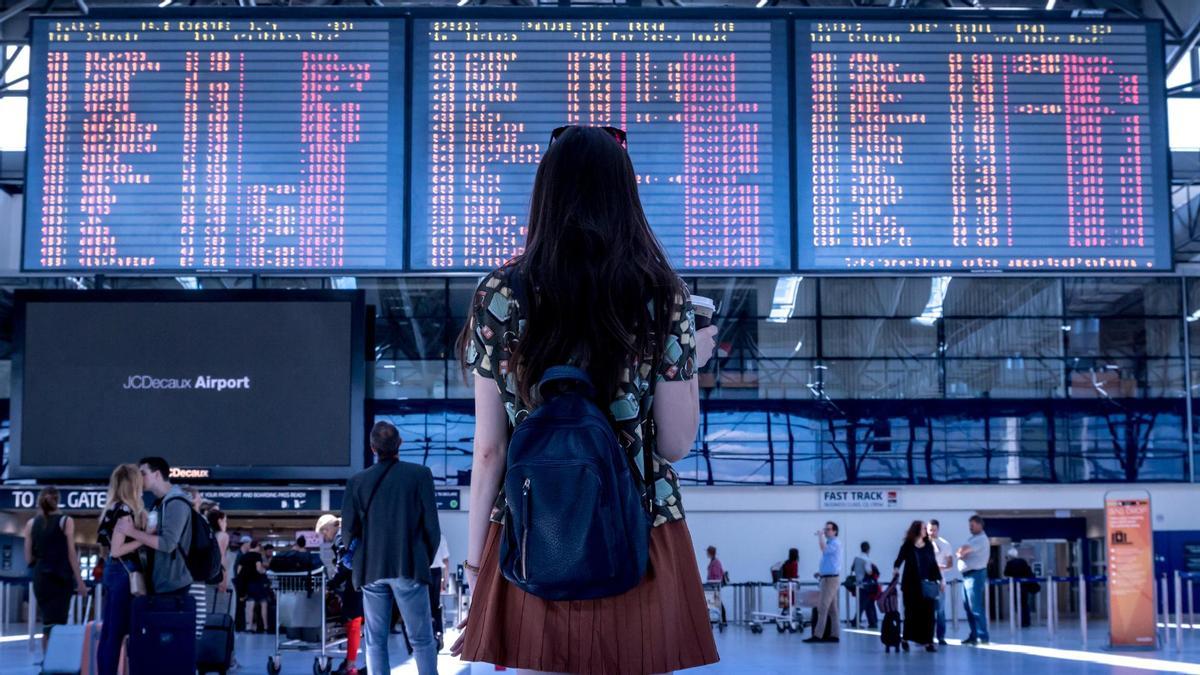 Una joven viendo las pantallas en un aeropuerto.