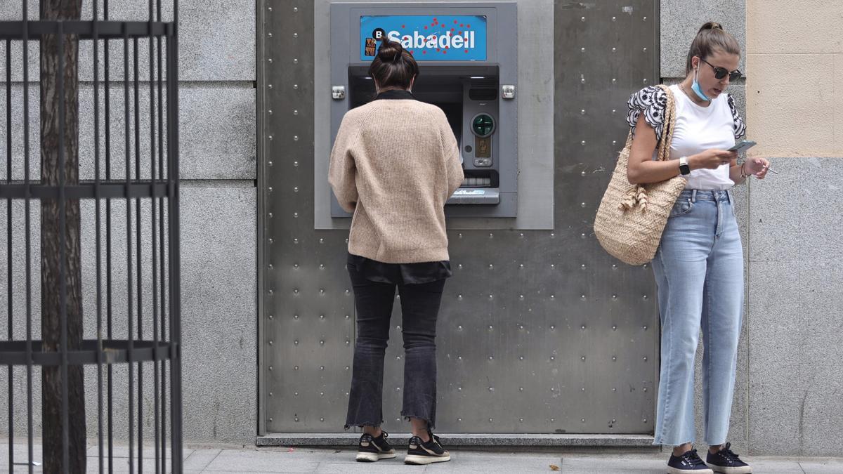 Dos mujeres en un cajero de una sucursal de banco Sabadell