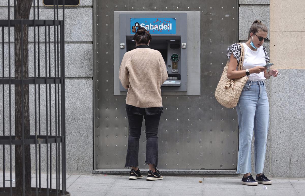 Archivo - Dos mujeres en un cajero de una sucursal de banco Sabadell