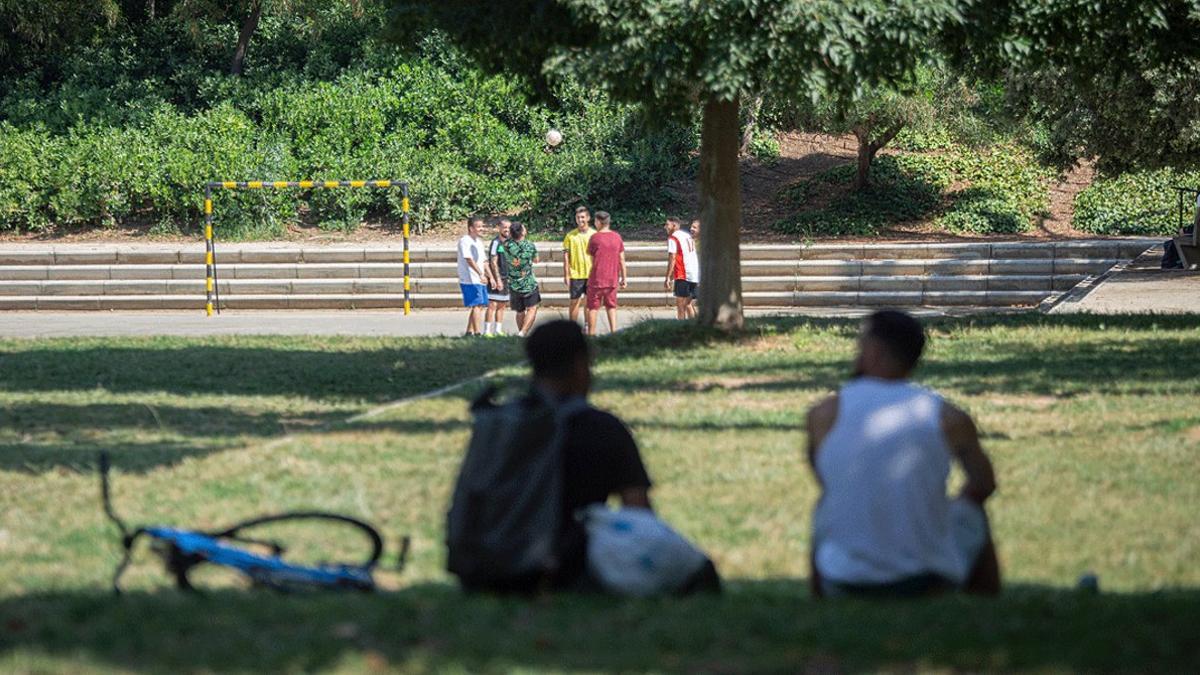 Varios jóvenes descansan o hacen deporte en un parque de Barcelona.