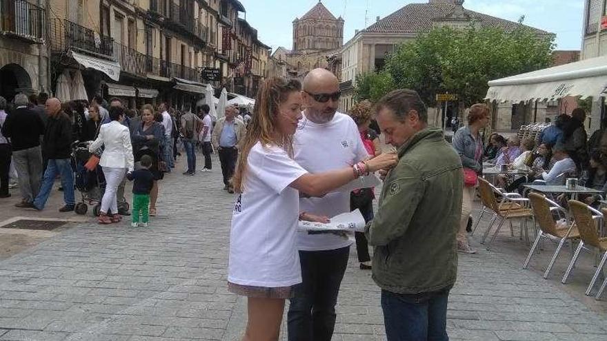 Dos voluntarios colocan una pegatina de Monte la Reina a un vecino.