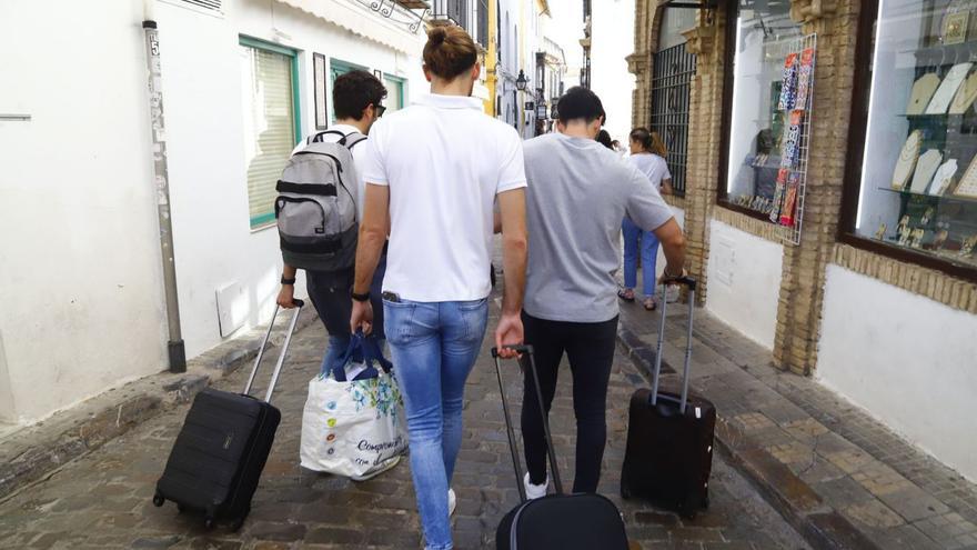 Jóvenes turistas se desplazan con sus maletas por el casco histórico de Córdoba.